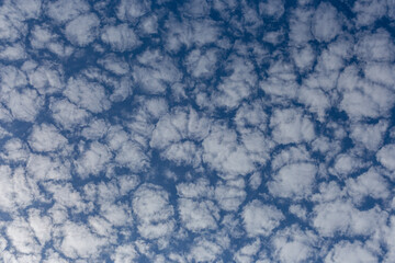 White fluffy clouds on a summer blue sky in cartoon style for background or wallpaper design. The background is white of round clouds in a blue sky.