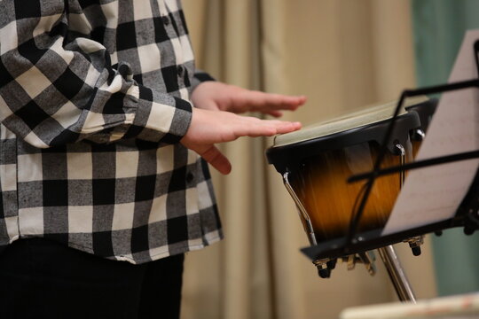 A person playing percussion in a plaid shirt background image close-up