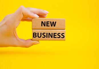 New business symbol. Concept words New business on wooden blocks. Beautiful yellow background. Businessman hand. Business and New business concept. Copy space.