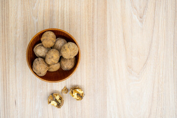 Walnuts in a bowl with a few cracked next to it on the table. Flat lay.