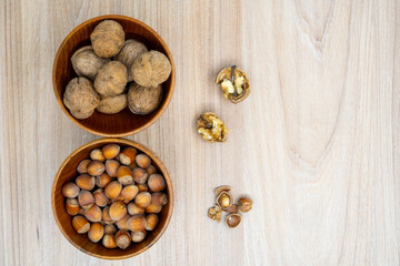 Hazelnuts and walnuts in a bowl with a few cracked next to it on the table. Flat lay.