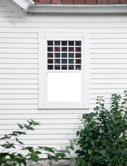 An exterior view of a hatched window on a white house