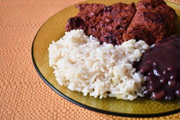 Carne adobada acompañada de frijoles negros y arroz blanco, comida tradicional de Guatemala.