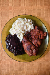 Carne adobada acompañada de frijoles negros y arroz blanco, comida tradicional de Guatemala. Toma Cenital.