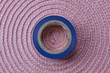 Fototapeta na wymiar one skein of blue plastic tape lies on a pink table