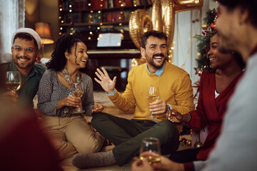 Cheerful man has fun while drinking wine with his friends on New Year's party at home.