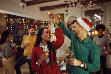 Young carefree couple dancing during Christmas party at home.