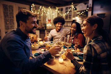 Happy couple toasting with wine during Thanksgiving dinner with friends.