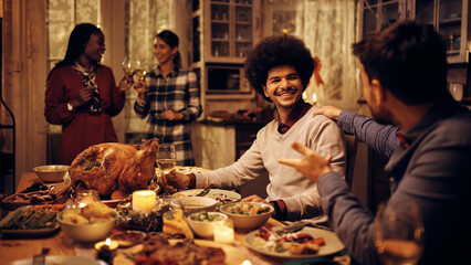 Fototapeta na wymiar Happy Middle Eastern man enjoys in Thanksgiving dinner with friends at dining table.