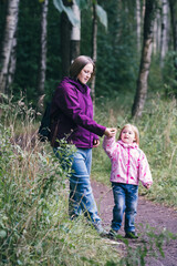 Mother and little preschooler girl walking in park.