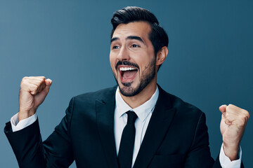 Business man happy smile with teeth open mouth raised hands up fists bump winner on blue background in business suit. 