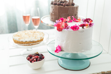 decoration with cakes, pie, glasses with champagne and fruit, table served for celebration, pastry shop with fresh food, details and background
