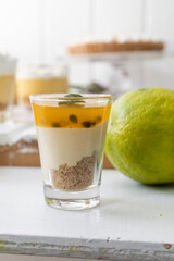glass cup with cheesecake and cream with cinnamon, gourmet dessert on a table, delicious food next to a lemon, ingredient