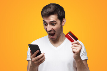 Angry man, holding credit card and phone, shouting having problem with bank account or money