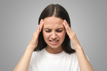 Upset unhappy woman squeezing head with hands, suffering from headache, tension and migraine