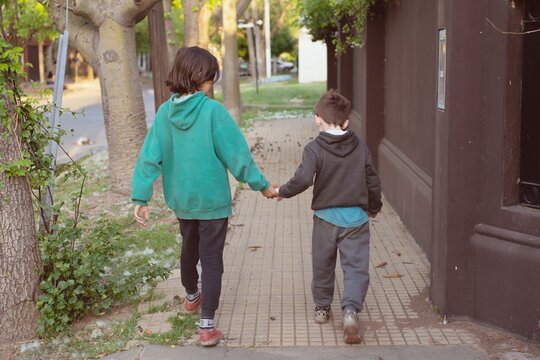 Ni&ntilde;os caminando de la mano por la vereda