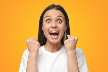 Woman shouting while her team win, raised both fist in victory gesture on yellow background
