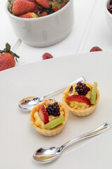 details of dessert decorated with strawberries, blackberries and pastry cream, wallpaper of elegant plates with silver spoons, pastries