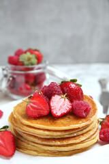 Tasty pancakes with fresh berries and honey on table, closeup. Space for text
