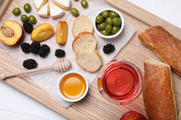 Glass of delicious rose wine and snacks on white wooden table, top view