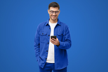 Smiling man wearing casual blue shirt looking at phone