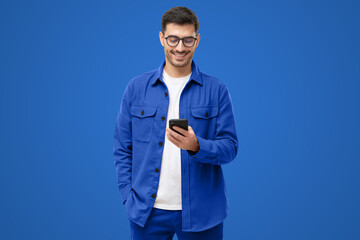 Smiling man wearing casual blue shirt looking at phone