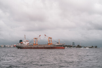 View of a huge Turkish freighter in the ocean; a big cargo ship in the waters of Male not far from the main island of Maldives, a warm cloudy day