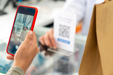 Medical pharmacy and contactless payment concept. Asian woman patient customer using mobile phone scan QR code on counter making online baking payment buying medicine and supplements in drugstore.