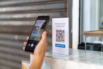 Asian woman enjoy shopping at street market on summer holiday vacation. Attractive girl using mobile phone scan QR code on bar counter making online payment buying iced coffee at outdoor coffee shop.