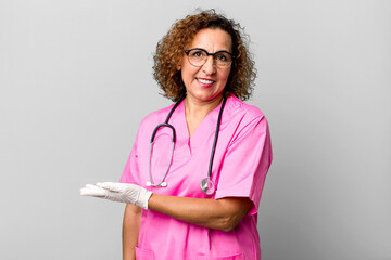 pretty middle age woman smiling cheerfully, feeling happy and showing a concept. nurse concept - obrazy, fototapety, plakaty