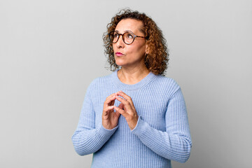 middle age hispanic woman scheming and conspiring, thinking devious tricks and cheats, cunning and...