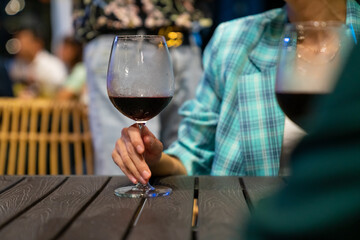 Happy Asian couple celebrating holiday event at luxury restaurant in the city at night. Man and woman enjoy city lifestyle having dinner and drinking wine together at bar terrace on travel vacation