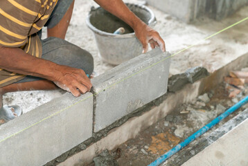 Hand of mansonry install concrete brick for wall of building.
