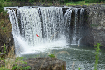 A men is diving from a cliff at Jingbo Lake falls in Heilongjiang, China. Waterfall and Mountain landscape.