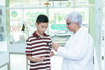 Obraz premium Middle-aged ophthalmologist examining young boy and giving eye consultation to Asian boy