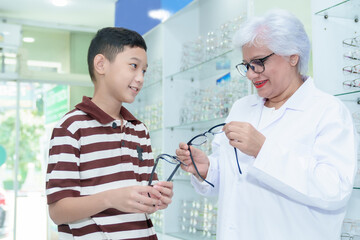 Obraz premium Middle-aged ophthalmologist examining young boy and giving eye consultation to Asian boy