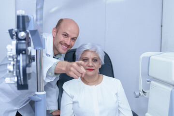 Obraz premium Attractive male ophthalmologist is checking eye vision of middle aged woman in modern clinic, doctors and ophthalmology clinic patients.