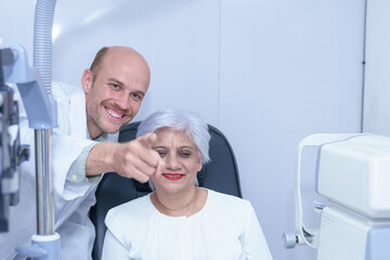 Obraz premium Attractive male ophthalmologist is checking eye vision of middle aged woman in modern clinic, doctors and ophthalmology clinic patients.