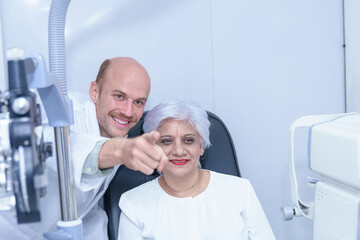 Obraz premium Attractive male ophthalmologist is checking eye vision of middle aged woman in modern clinic, doctors and ophthalmology clinic patients.