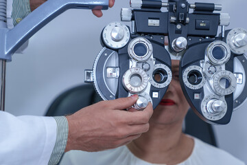 Attractive male ophthalmologist is checking eye vision of middle aged woman in modern clinic,...
