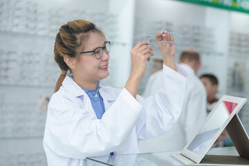 Female ophthalmologist holding eyeglasses and examining them, focus on eyeglasses, close-up