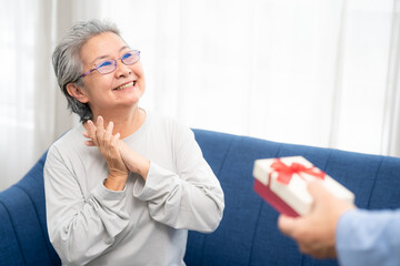 Happy senior woman feeling good when someone giving a gift box for herself. Happy Elderly Asian.