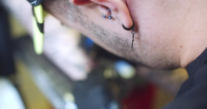 Back shot of a professional tattoo artist tattooing a man's arm inside a professional studio.