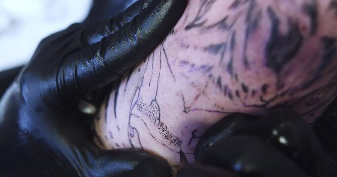Beautiful close-up slow motion detail of the tattooing process on a man's arm by a young professional tattoo artist.