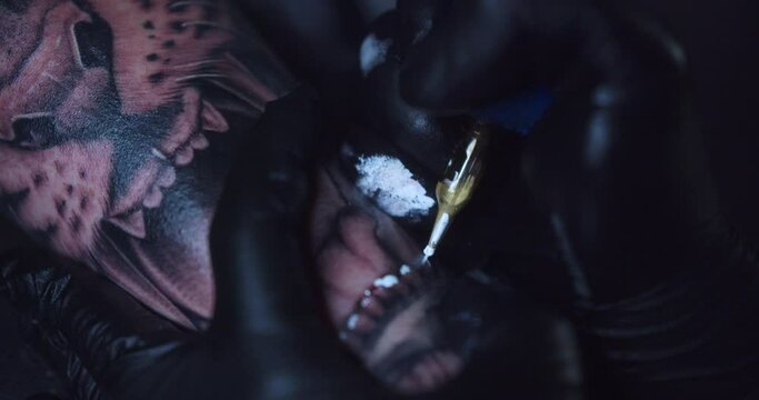 Close-up shot of a beautiful growling tiger design while being tattooed in white ink by a professional artist.