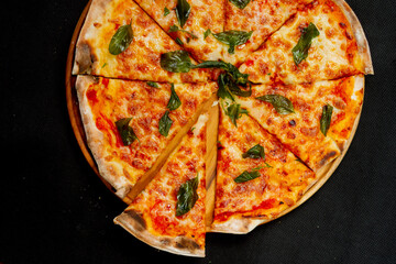 Supreme pizza slice on wooden board with black background.