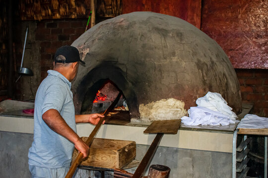 Baker cooking bread the traditional way, in a dome-shaped wood-fired oven, in Chilca - Peru