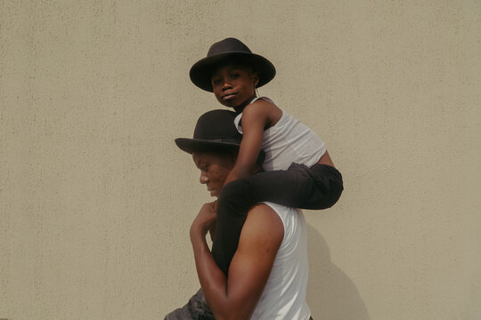 Man carry boy on shoulders both wearing hats