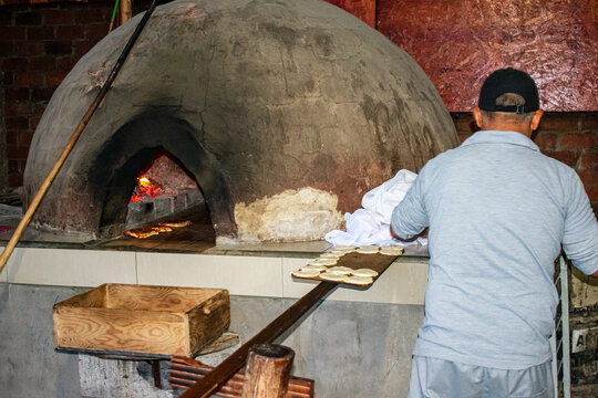 Baker cooking bread the traditional way, in a dome-shaped wood-fired oven, in Chilca - Peru