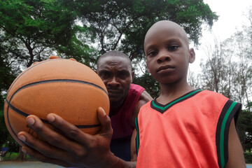 Boy standing beside father holding a basketball